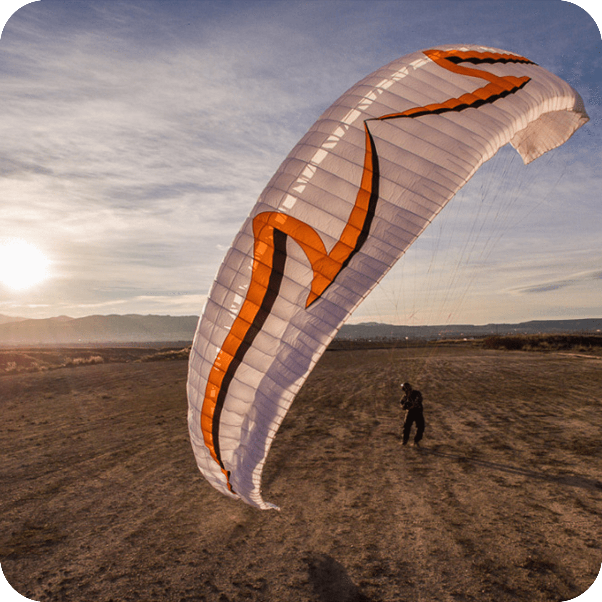 A paraglider wing glowing in golden sunset light over the Oklahoma horizon.