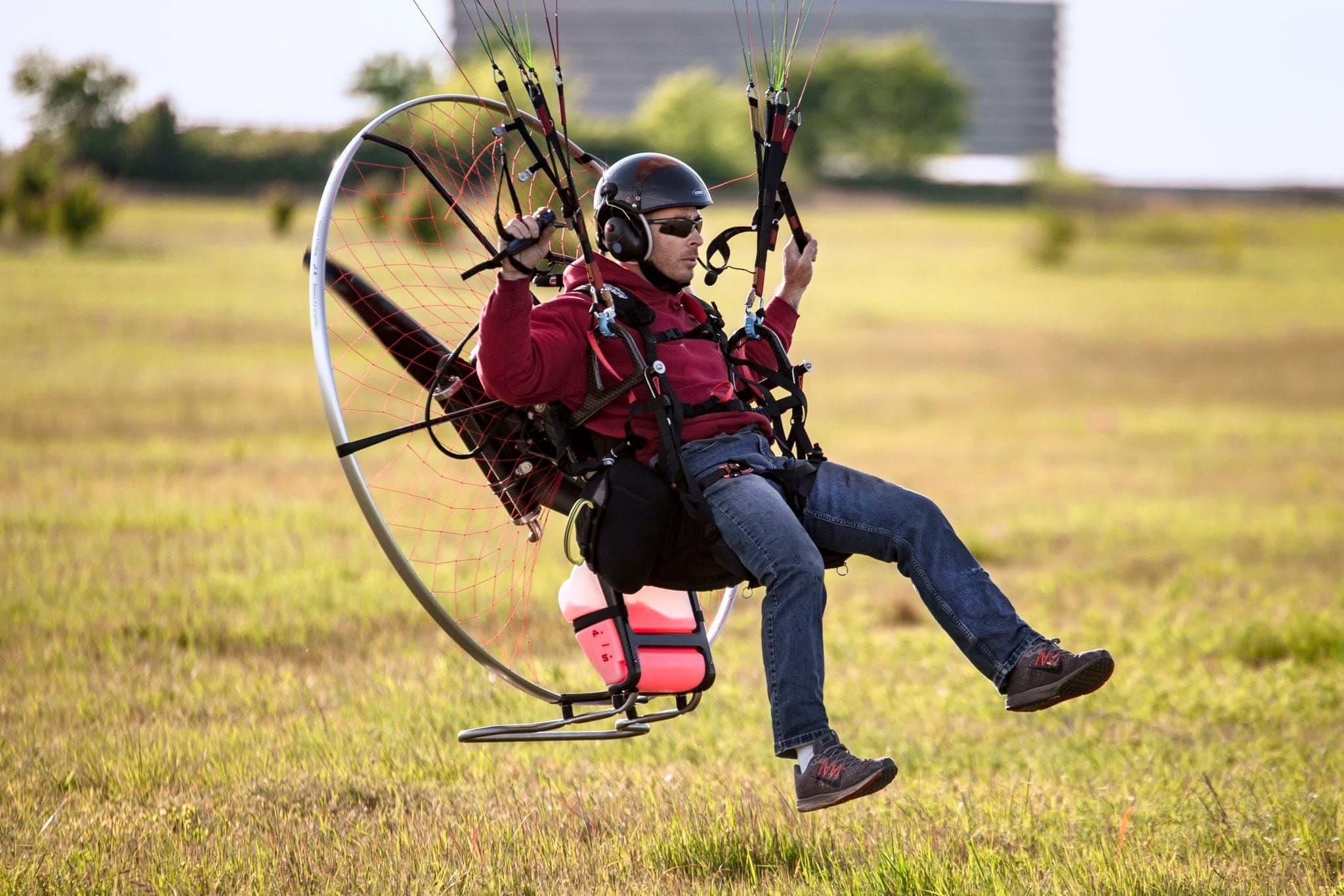 Shawn Elder flying his paramotor low over a green Oklahoma field in warm light.
