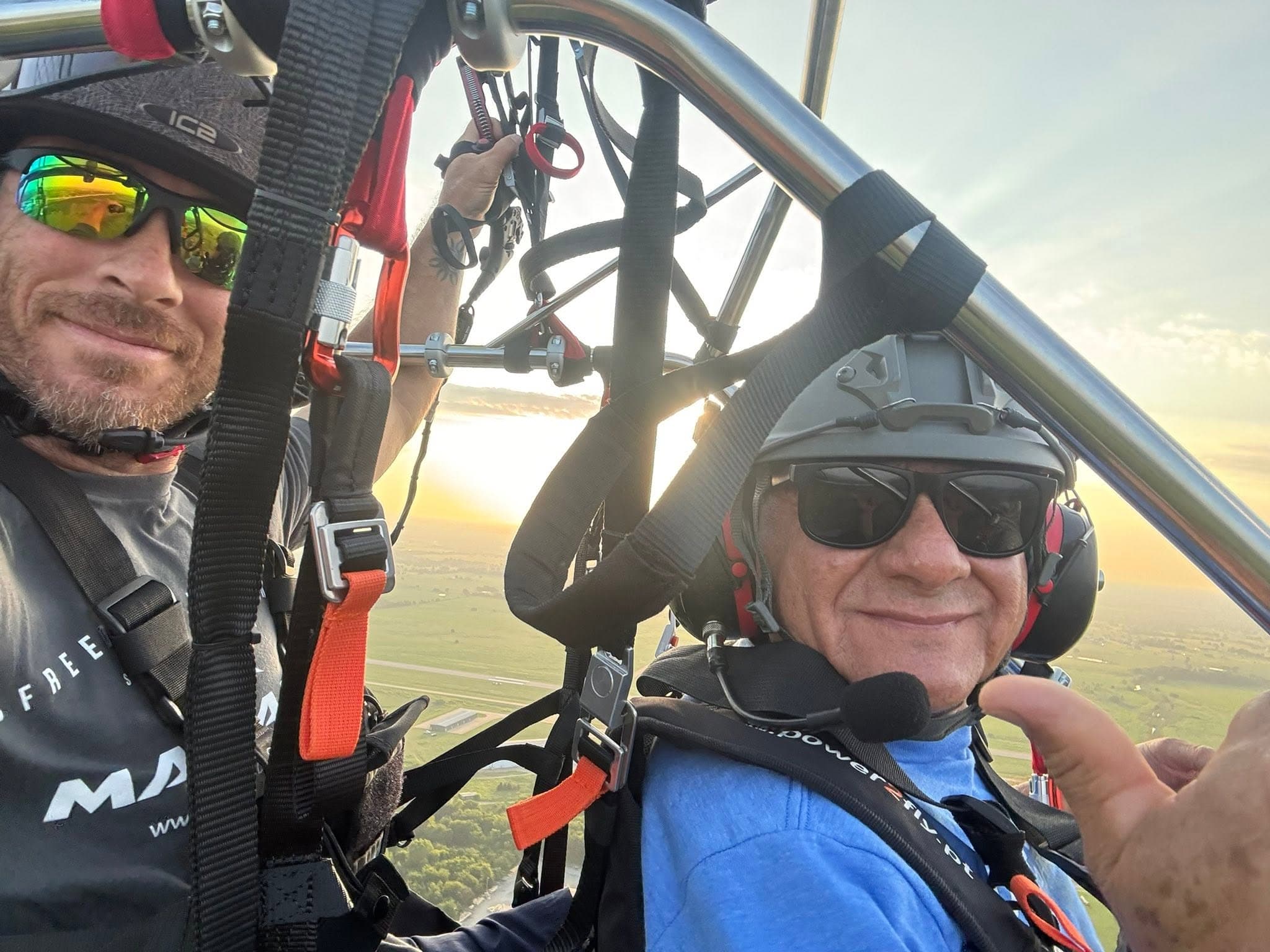 Shawn and a smiling passenger giving a thumbs-up mid-flight on a tandem paramotor at sunset over Durant, Oklahoma.